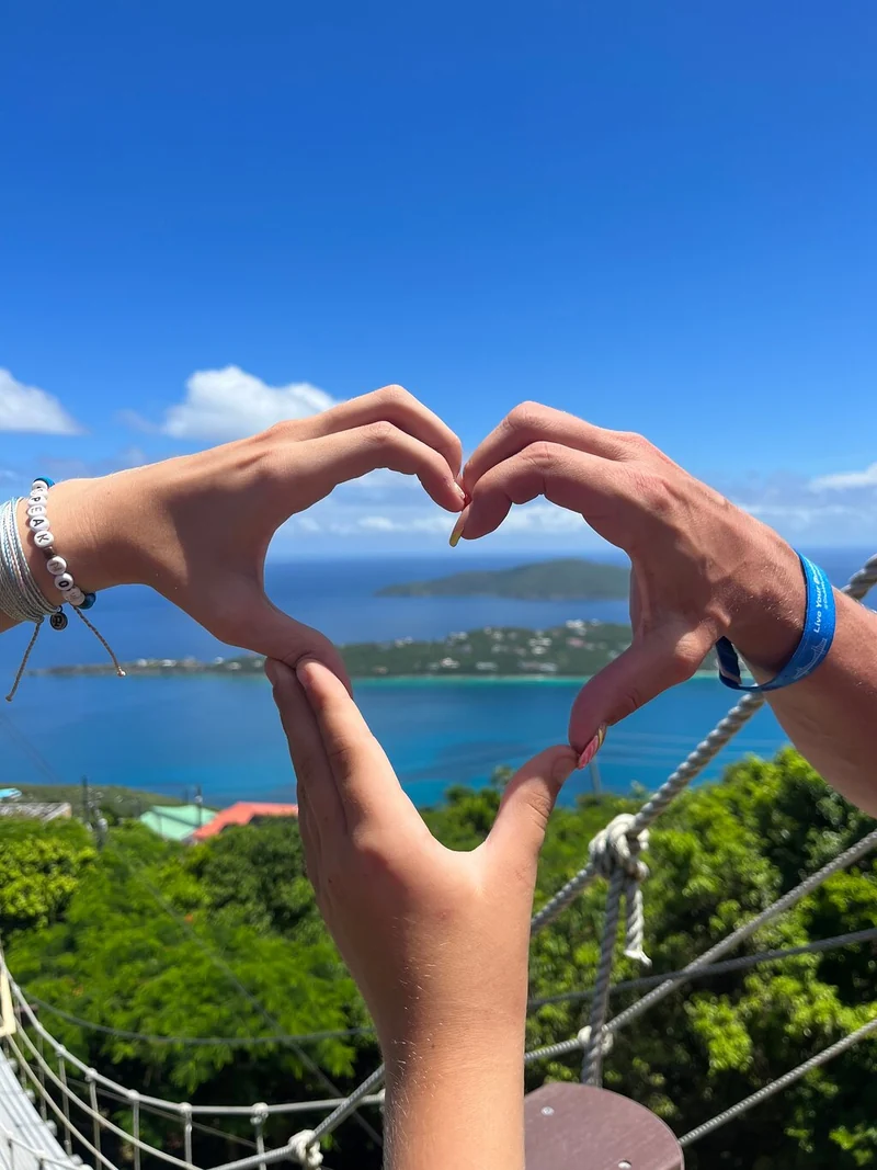 Unas manos formando un corazón sobre la vista de Magens Bay